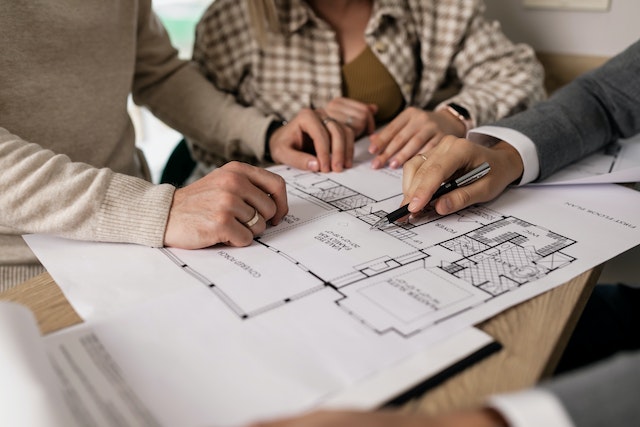 three people looking at the blueprint of a home